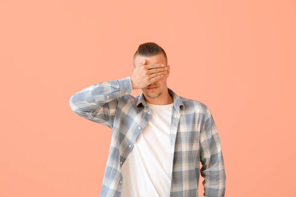 Young man covering his eyes on color background - Foto, Bild