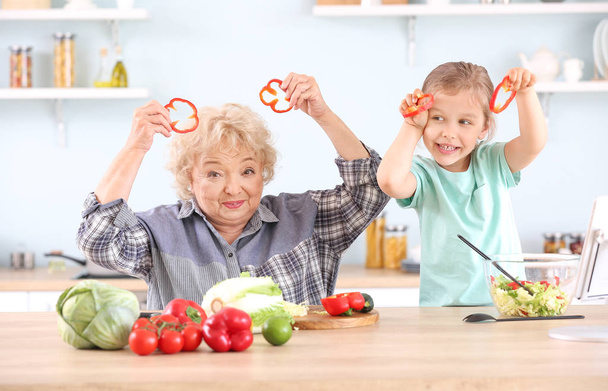 台所で楽しみを持っている祖母とかわいい女の子 - 写真・画像