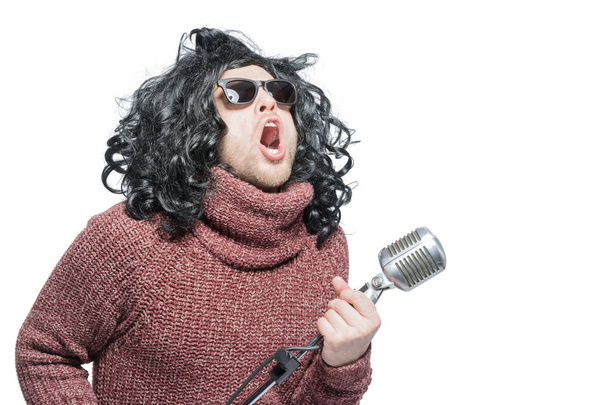 Singing man in a wig and sunglasses with a microphone. Close-up. - Фото, изображение