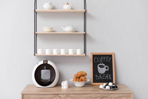 Modern coffee machine and croissants on kitchen table - Фото, изображение