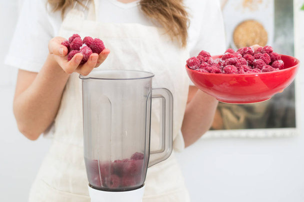 Raspberry Smoothies A woman puts fresh-frozen raspberry berries in a shaker. The concept of healthy eating. - Photo, Image