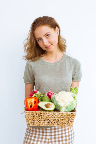Beautiful girl holding basket with fresh vegetables. Vegetarian, healthy eating concept. - Foto, imagen