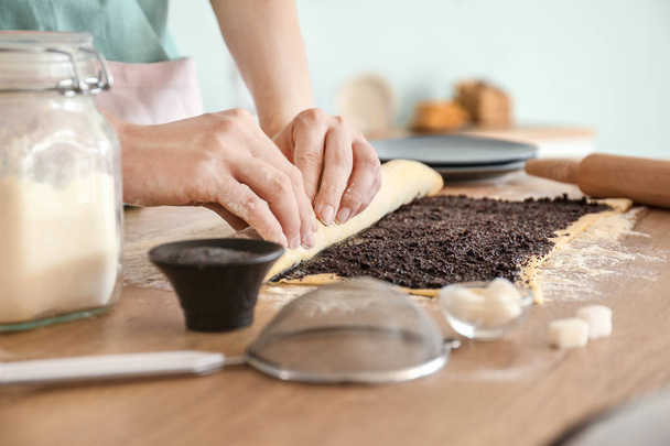 Femme préparant une délicieuse pâtisserie avec des graines de pavot à table
 - Photo, image