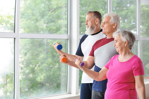Personas mayores entrenando con pesas en el gimnasio
 - Foto, imagen