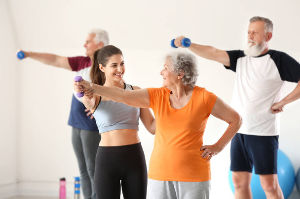 Starsi ludzie trenują z instruktorem w siłowni - Zdjęcie, obraz