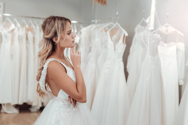 Thoughtful young woman choosing her wedding dress. - Foto, Bild