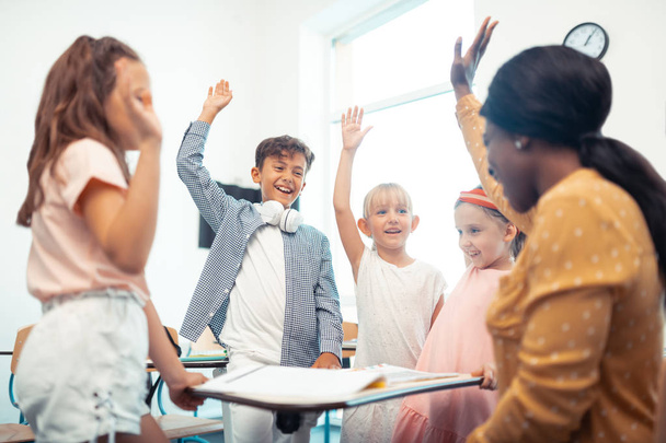 Niños y maestros levantando las manos mientras se divierten juntos
 - Foto, Imagen