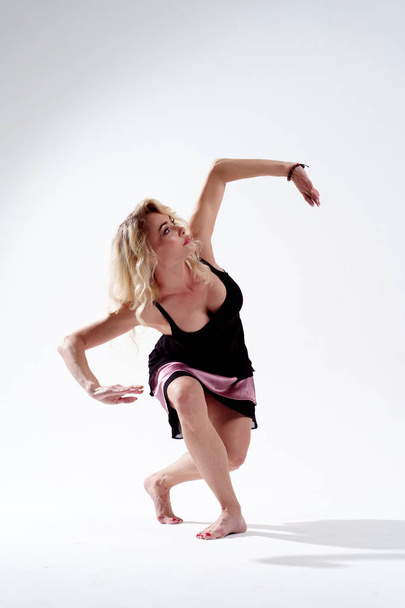Photo of long-haired blonde looking up engaged in dancing in studio on empty white background - Φωτογραφία, εικόνα