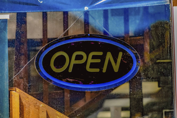 Cartel abierto detrás de la puerta de cristal de un establecimiento
 - Foto, imagen