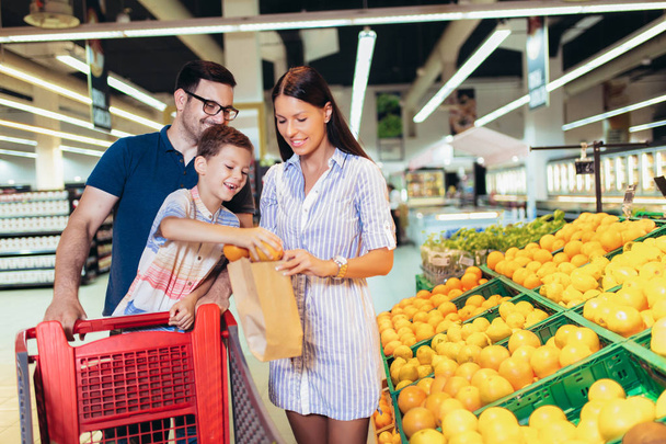 Família feliz com criança e carrinho de compras comprando comida no supermercado
 - Foto, Imagem