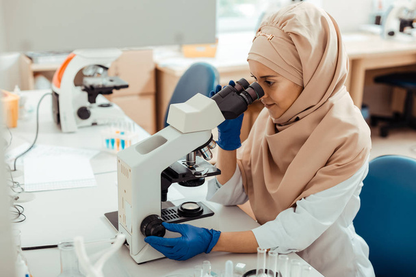 Intelligent muslim woman using the microscope for work - Foto, afbeelding