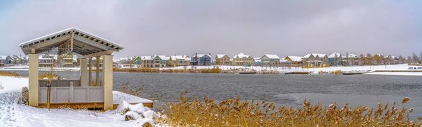 Περίπτερο στο χιόνι καλυμμένη ακτή της λίμνης που προβάλλονται σε μια συννεφιασμένη χειμερινή ημέρα - Φωτογραφία, εικόνα