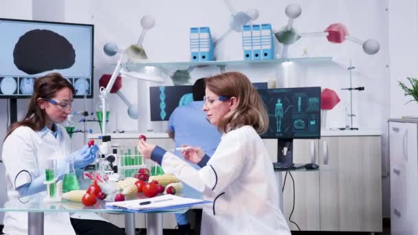 Investigadora femenina inyectando muestras de OMG en fresas
 - Metraje, vídeo