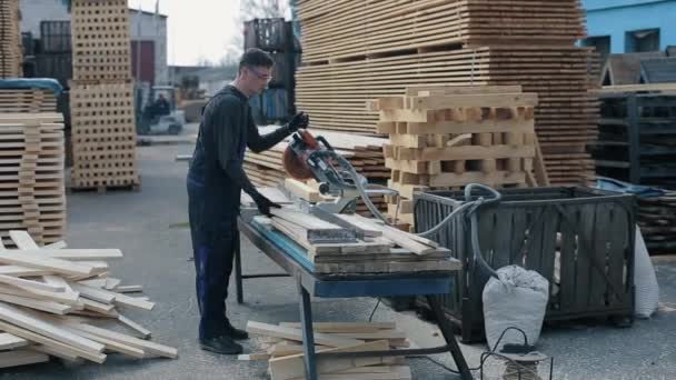 Промышленный молодой плотник, использующий лесопилку. Человек режет деревянные доски
. - Кадры, видео