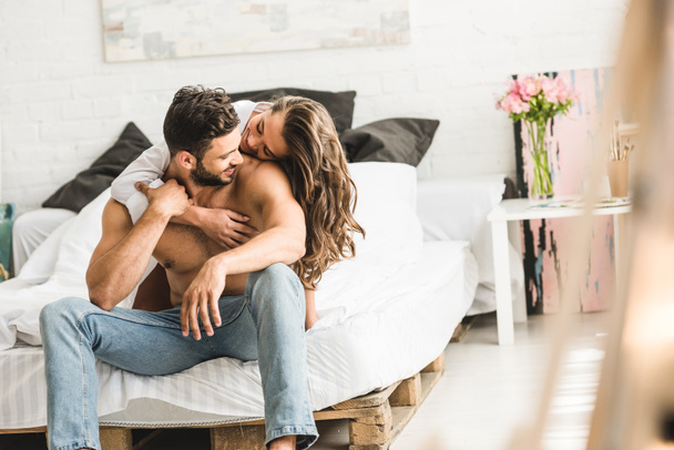 giovane coppia che si abbraccia mentre si siede a letto e si guarda
 - Foto, immagini