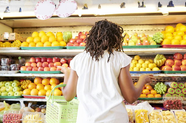 Birçok meyve ve çilek ile süpermarket raflarında bakarak Şaşkın genç kadın - Fotoğraf, Görsel