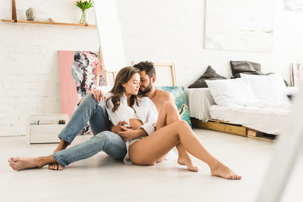 selective focus of sexy couple sitting on floor while man hugging girl from back - Photo, Image