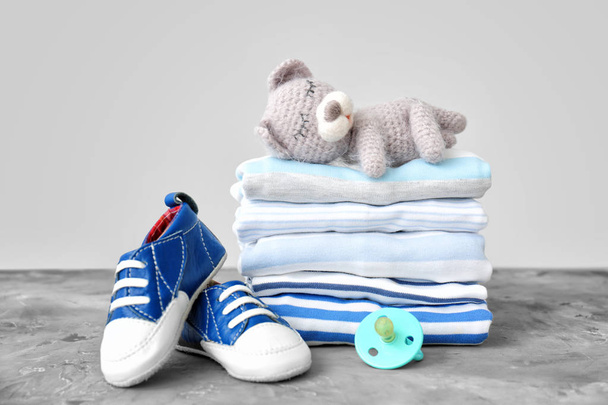 Empilement de vêtements de bébé, chaussures, jouets et sucette sur la table
 - Photo, image