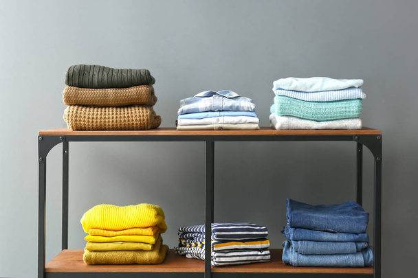 Stacked clothes on shelves against grey background - Fotó, kép