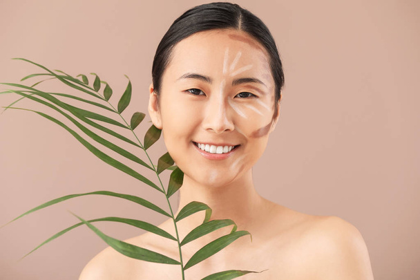 Femme asiatique avec contouring maquillage et feuille tropicale sur fond de couleur
 - Photo, image