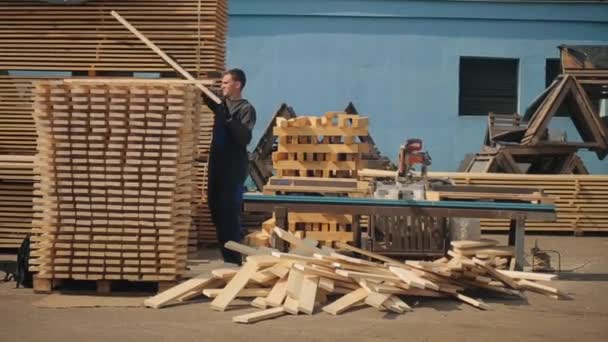 Man folds wooden planks. Stacks of square wood planks for furniture materials. - Footage, Video