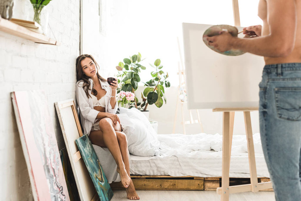 selektywne skupienie dziewczyny siedzącej w łóżku z winem i mężczyzną rysunek dziewczyna - Zdjęcie, obraz