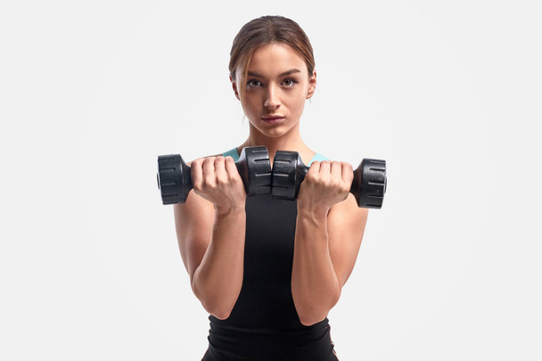 Athletic female exercising with dumbbells - Foto, afbeelding