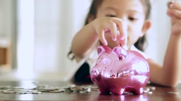 Ładna dziewczyna, wprowadzenie monety do piggy bank w domu - Materiał filmowy, wideo