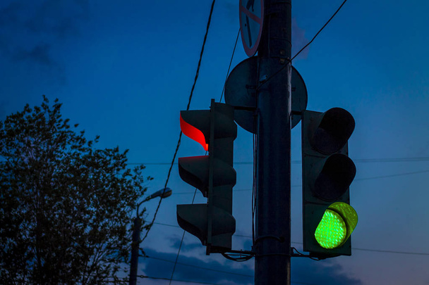 traffic light with a burning green light allowing movement against the evening time at dusk - Fotó, kép