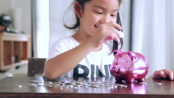 Linda chica poniendo monedas en alcancía en casa
 - Metraje, vídeo