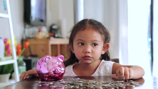 Χαριτωμένο κορίτσι βάζοντας κέρματα σε κουμπαρά στο σπίτι - Πλάνα, βίντεο