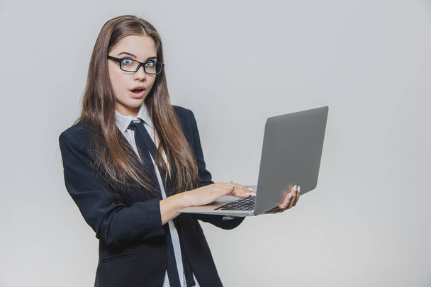 Beautiful young businesswoman is wearing glasses and using a modern computer touchscreen. Confident female employer is working and is concentrated. Girl is looking at the camera and is shocked. - Foto, Bild