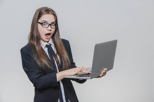 Beautiful young businesswoman is wearing glasses and using a modern computer touchscreen. Confident female employer is working and is concentrated. Girl is looking at the camera. Being shocked she is - Zdjęcie, obraz