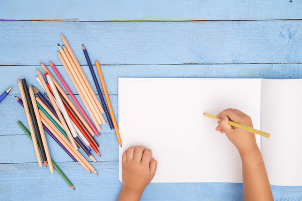 青いタベルのアルバムに鉛筆で描く子供の手 - 写真・画像