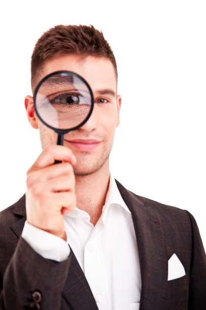 Young business man in suit looking to magnifying glass - Foto, Imagen