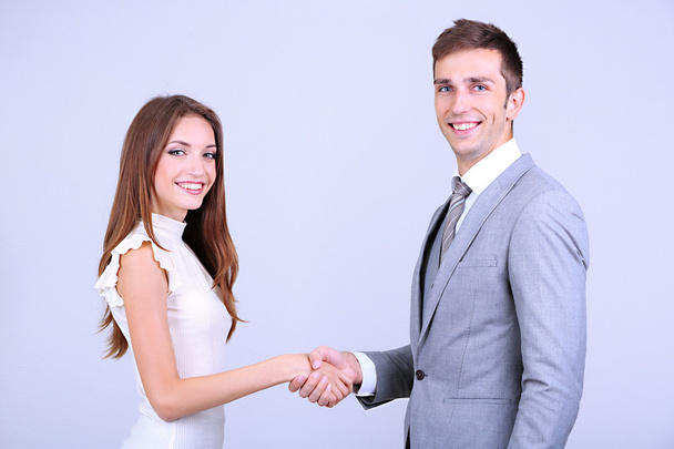 Business colleagues shaking hands on grey background - Photo, Image