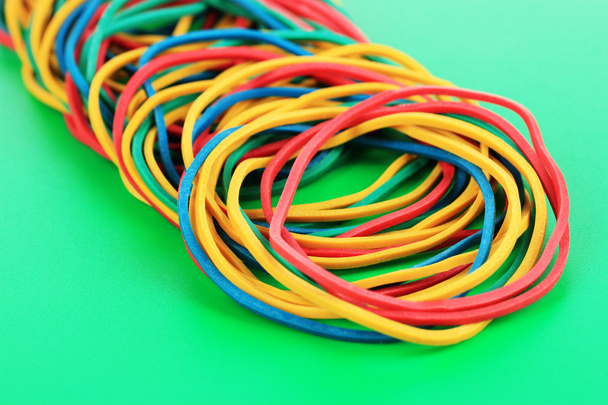 Colorful rubber bands on green background - 写真・画像