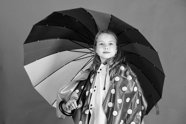Waterproof accessories make rainy day cheerful and pleasant. Kid girl happy hold colorful umbrella wear waterproof cloak. Enjoy rainy weather with proper garments. Waterproof accessories manufacture - Zdjęcie, obraz