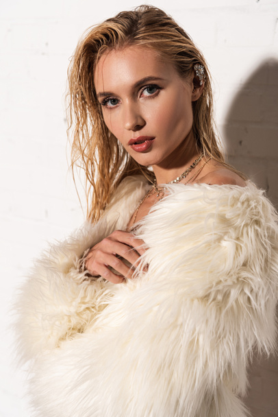 sexy young woman with wet hair in white faux fur coat on white background - Φωτογραφία, εικόνα