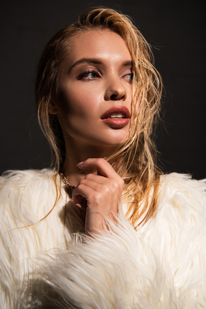 sexy young woman with wet blonde hair in white faux fur coat isolated on black - Fotografie, Obrázek