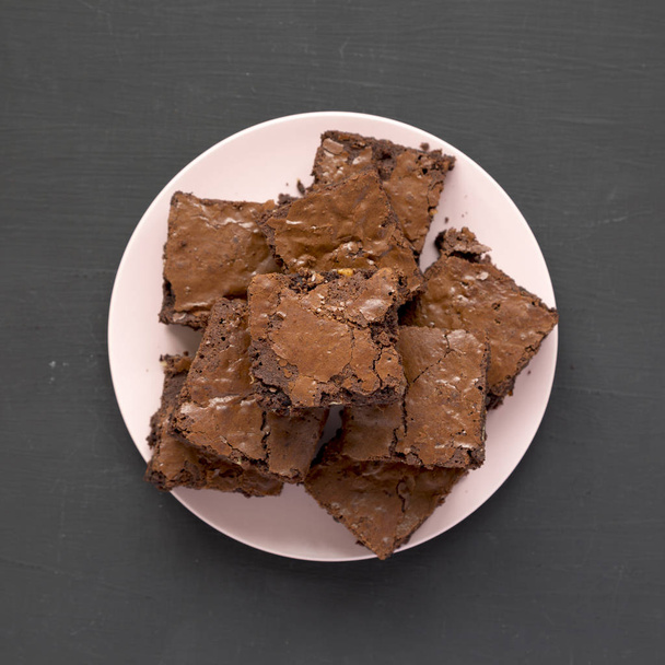 Vue de dessus, brownies au chocolat faits maison sur une assiette rose sur un noir
 - Photo, image