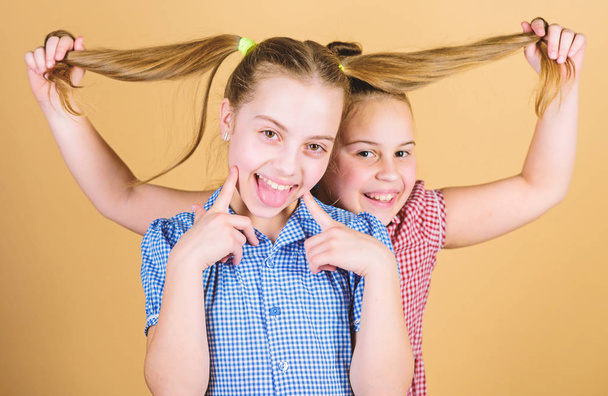 Adding care to her hair. Playful little girl keeping long hair of adorable baby. Cute happy kid with fashionable hair ponytails. Small child smiling with blond hair - Photo, image