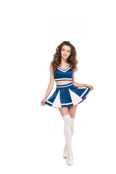 sexy happy cheerleader girl in blue uniform holding skirt isolated on white - Fotó, kép