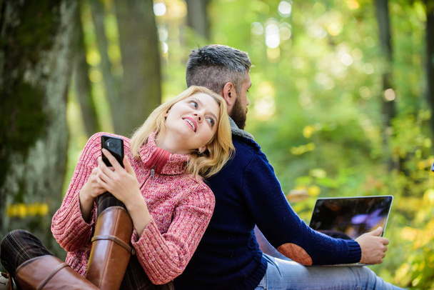 Happy loving couple relaxing in park with mobile gadgets. Modern people always involved online communication. Internet addiction. Online life modern technology. Logout of all accounts. Modern life - Photo, Image