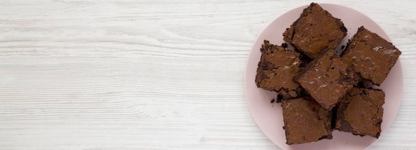 Zelfgemaakte chocolade brownies op een roze bord op een witte houten ta - Foto, afbeelding