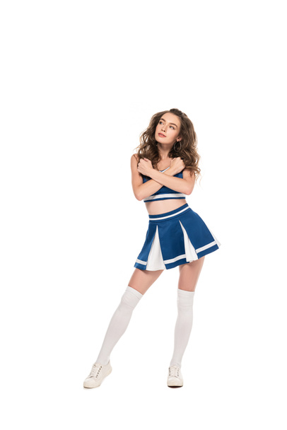 sexy dreamy cheerleader girl in blue uniform with crossed arms looking away isolated on white - Foto, imagen