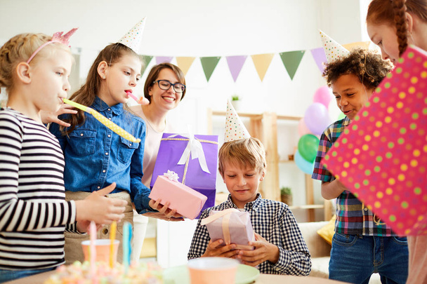 Retrato de niño feliz recibiendo regalos rodeados de amigos durante la fiesta de cumpleaños, espacio para copiar
 - Foto, imagen