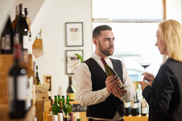 Waist up portrait of professional sommelier choosing wine for client in restaurant, copy space - Photo, Image