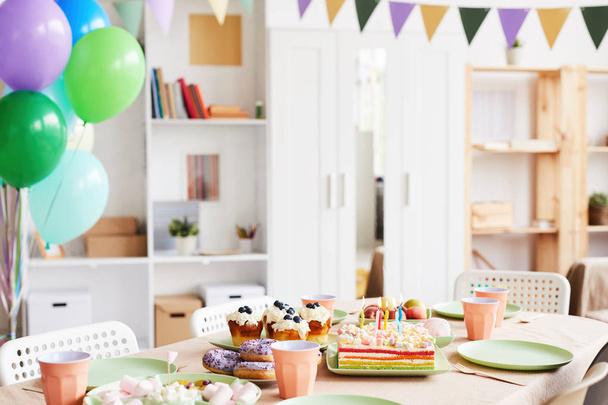 Achtergrondafbeelding van diner tafel set met snoep en cake voor verjaardagsfeestje in ingerichte kamer, ruimte kopiëren - Foto, afbeelding