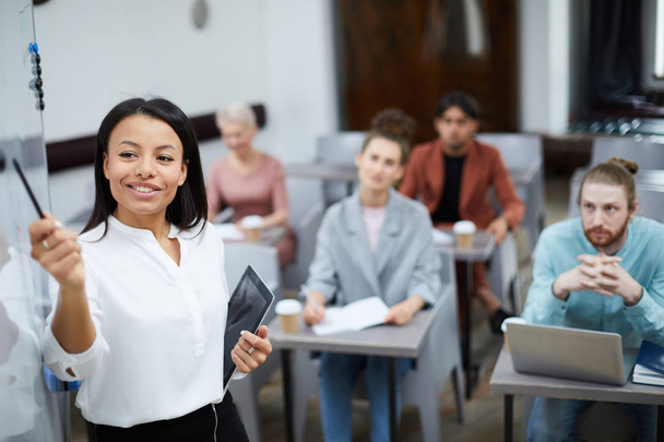 Cintura-se retrato de mulher de negócios sorridente apontando para quadro branco ao apresentar curso de formação para estudantes em classe, espaço de cópia
 - Foto, Imagem